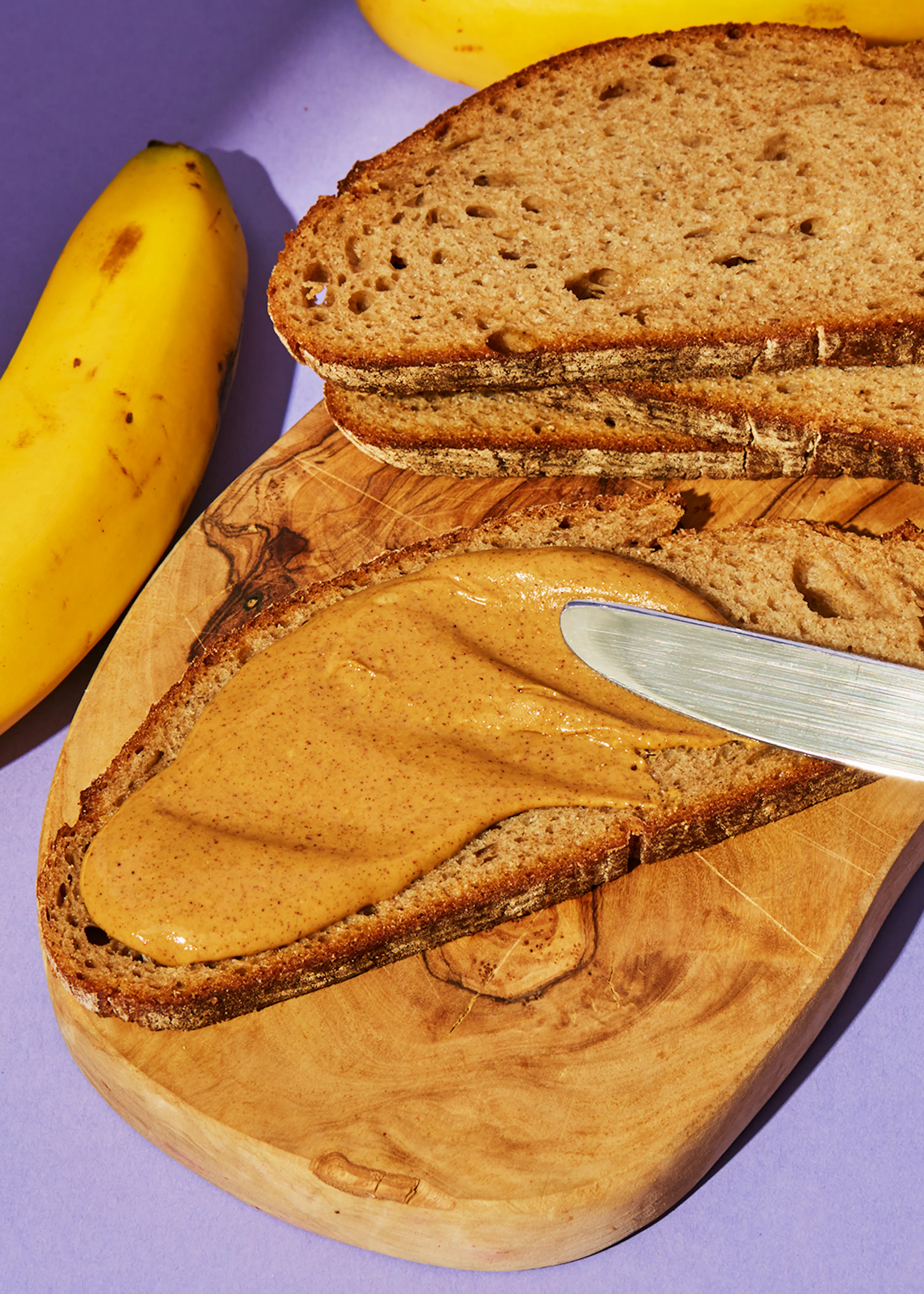 ein Stück Brot mit Erdnussbutter und einem Messer auf einem Schneidebrett